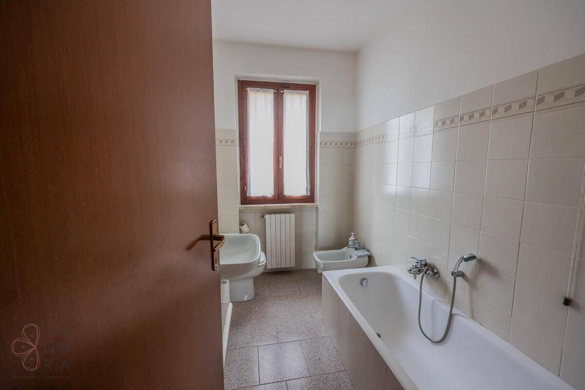 Badezimmer mit Badewanne, WC, Bidet und einem Fenster für natürliche Belüftung und Licht.