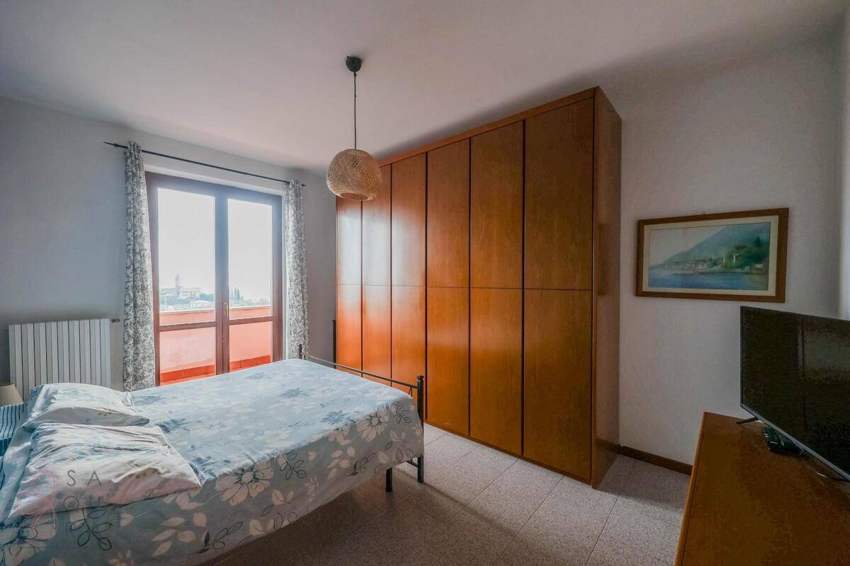 Schlafzimmer mit großem Holzkleiderschrank, Doppelbett und Zugang zu einem Balkon.