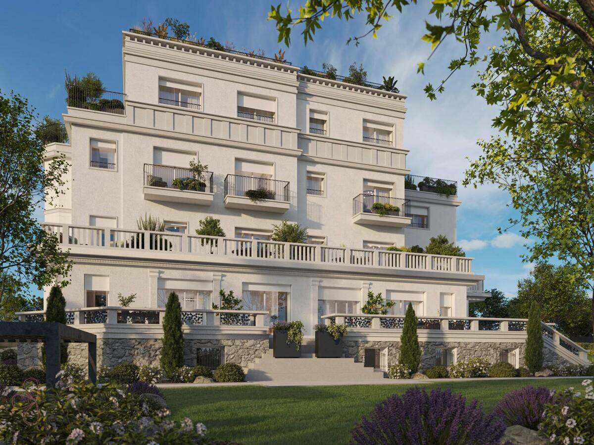 Elegante weiße Fassade eines Gebäudes mit Balkonen und einem gepflegten Gartenbereich im Vordergrund.