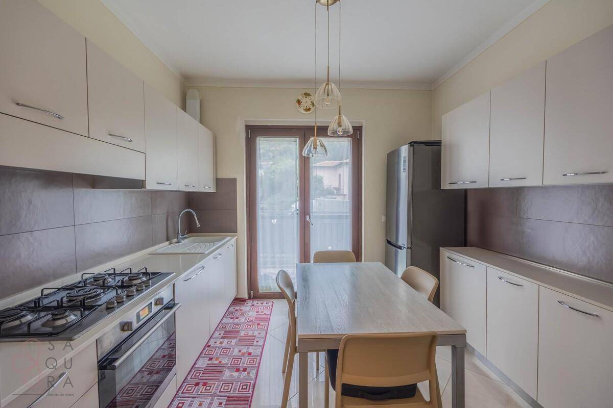 Funktionale Küche mit Gasherd, Esstisch und Zugang zu einem kleinen Balkon.