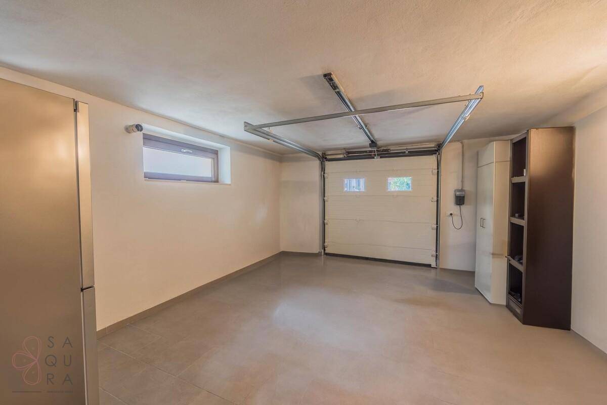 Geräumige Garage mit automatischem Tor, Fenster und ausreichend Platz für ein Fahrzeug.