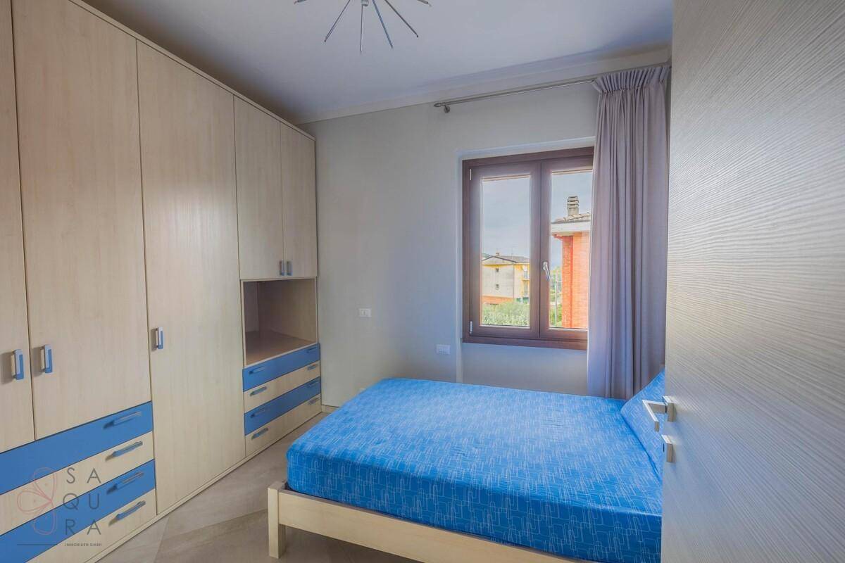 Kinderzimmer mit Einzelbett, Einbauschrank und Fenster mit Blick ins Grüne.