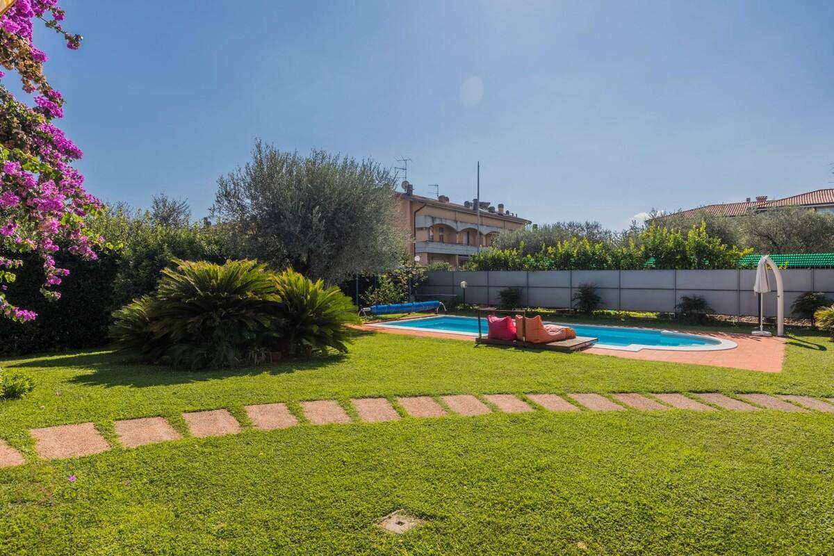 Weitläufiger Gartenbereich mit Pool, Liegeflächen und umgebender Hecke für Privatsphäre.