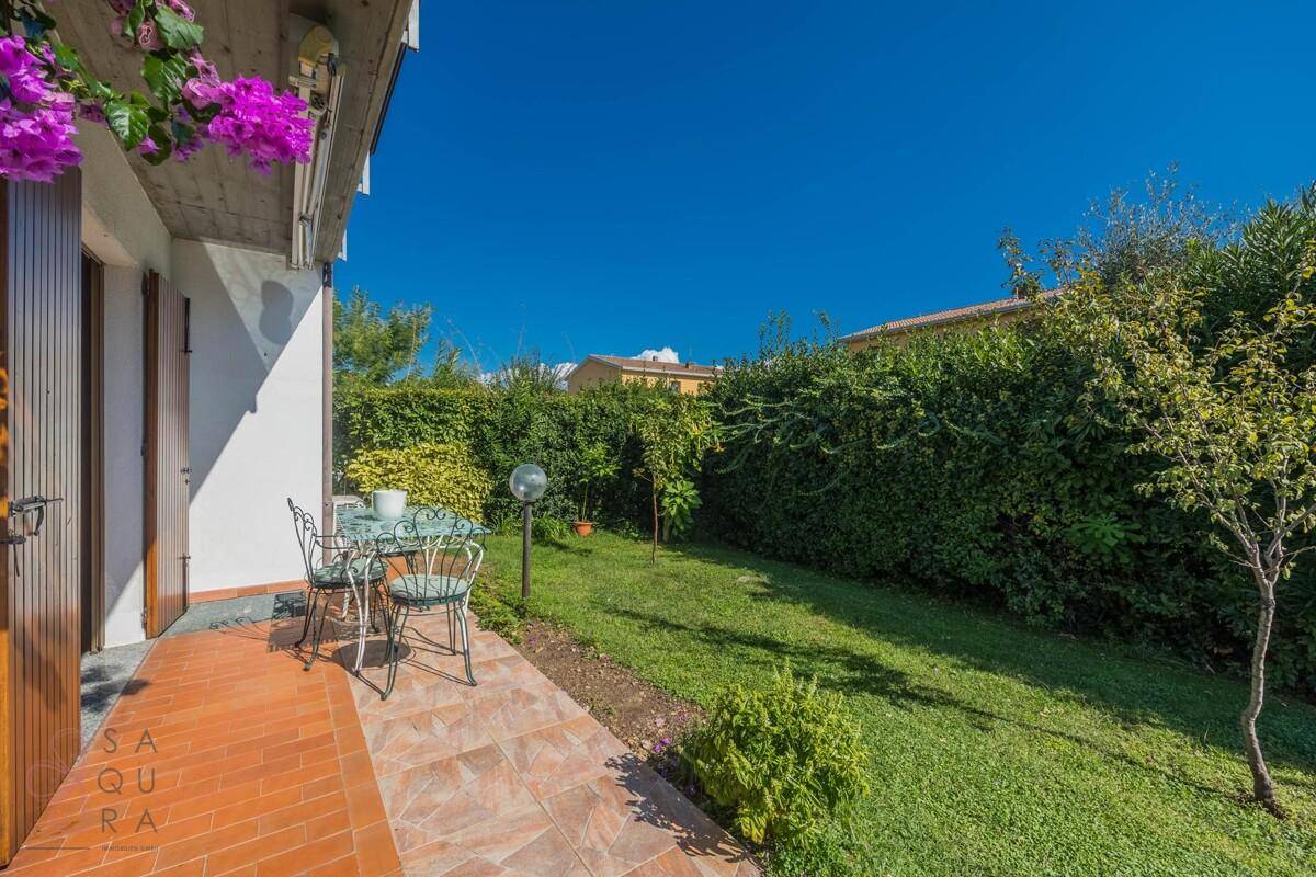 Kleiner Gartenbereich mit gepflasterter Terrasse, Essgruppe und hoher Hecke für Privatsphäre.