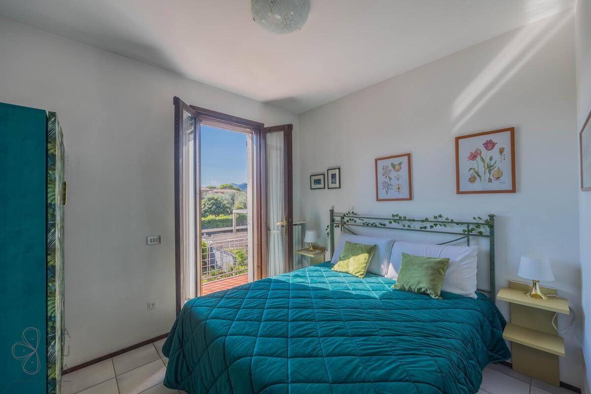 Helles Schlafzimmer mit Doppelbett, Fliesenboden und direktem Zugang zum Balkon.