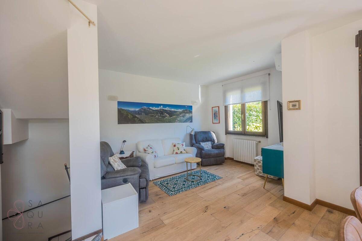 Gemütliches Wohnzimmer mit Holzboden, bequemen Sofas und Blick in den Garten.