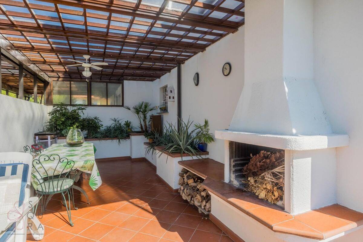 Gemütliche überdachte Terrasse mit Essbereich, Kamin und Holzvorrat für Grillabende.