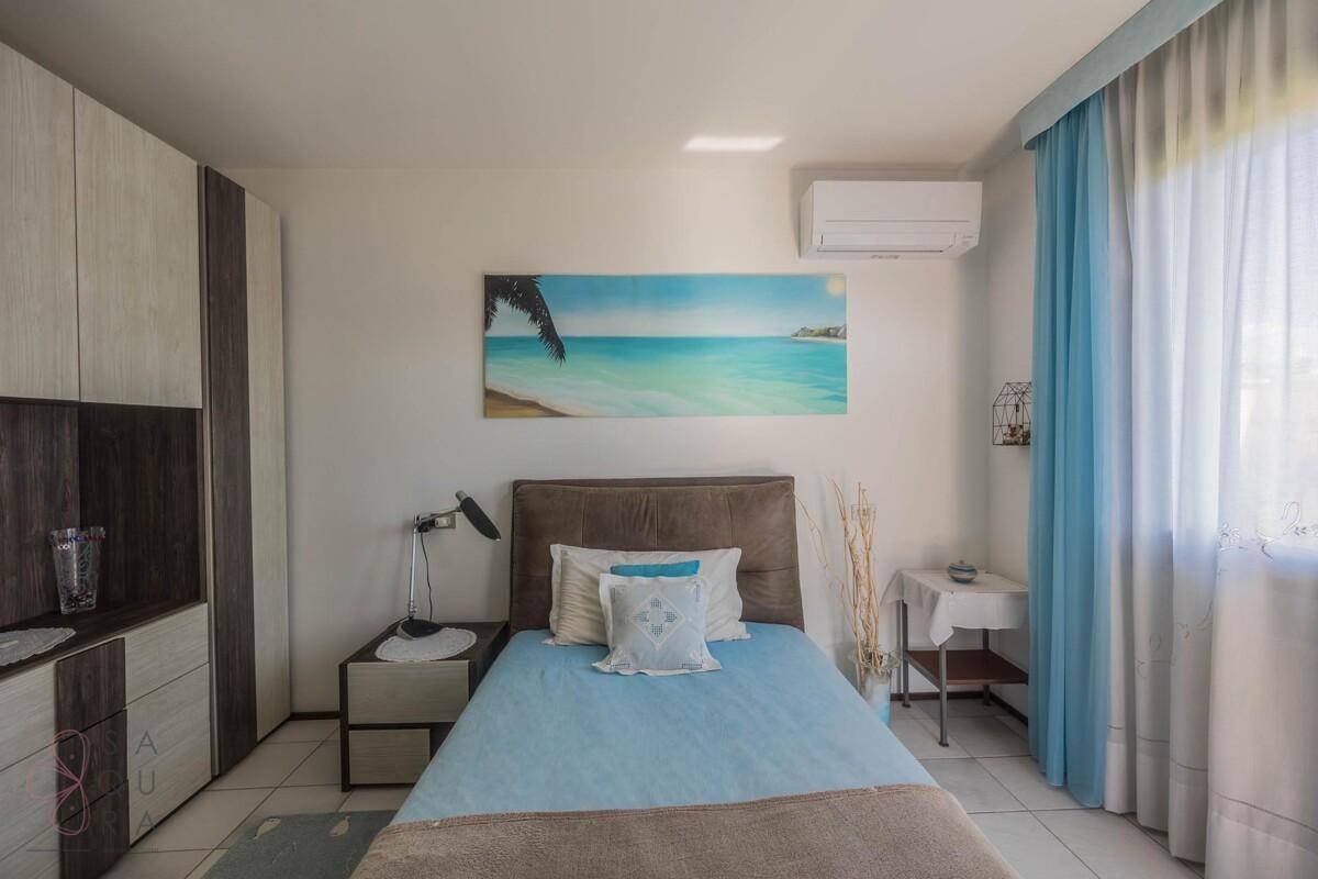 Helles Schlafzimmer mit Klimaanlage, Einbauschrank und Strandbild an der Wand.