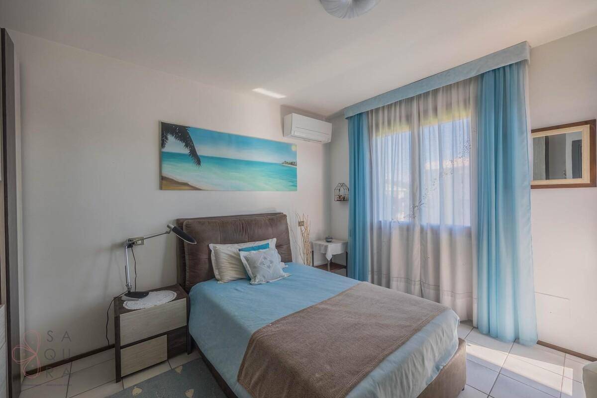 Schlafzimmer mit Einzelbett, Klimaanlage und hellblauen Vorhängen.