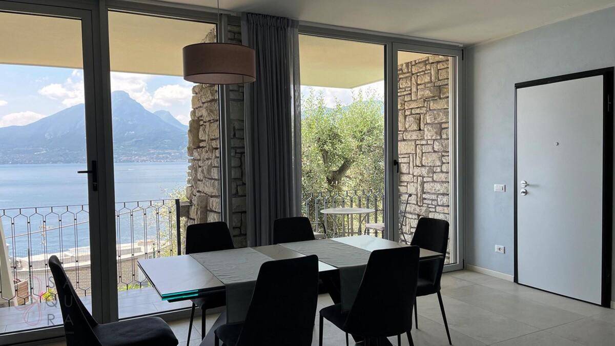 Essbereich mit Panoramablick auf den See und die Berge, umgeben von Steinmauern.