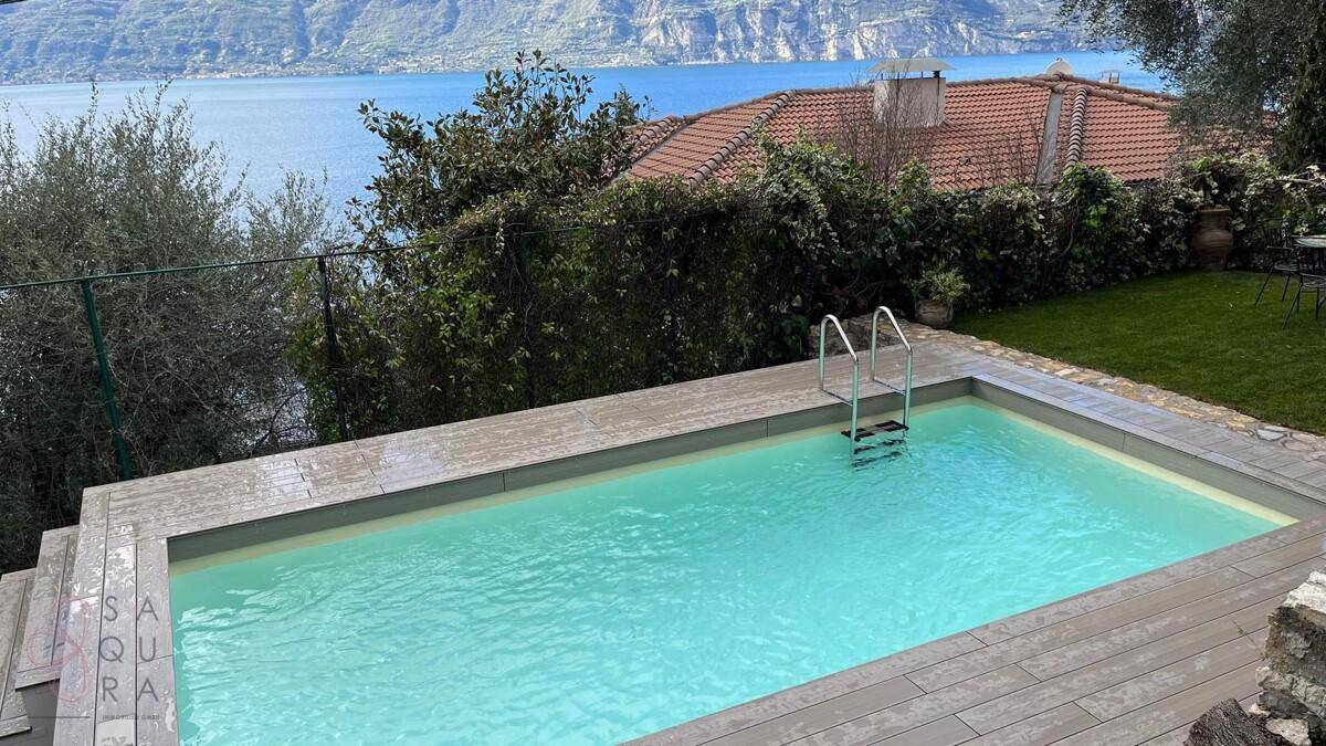 Außenpool mit Holzdeck und Blick auf den See und die umliegende Landschaft.