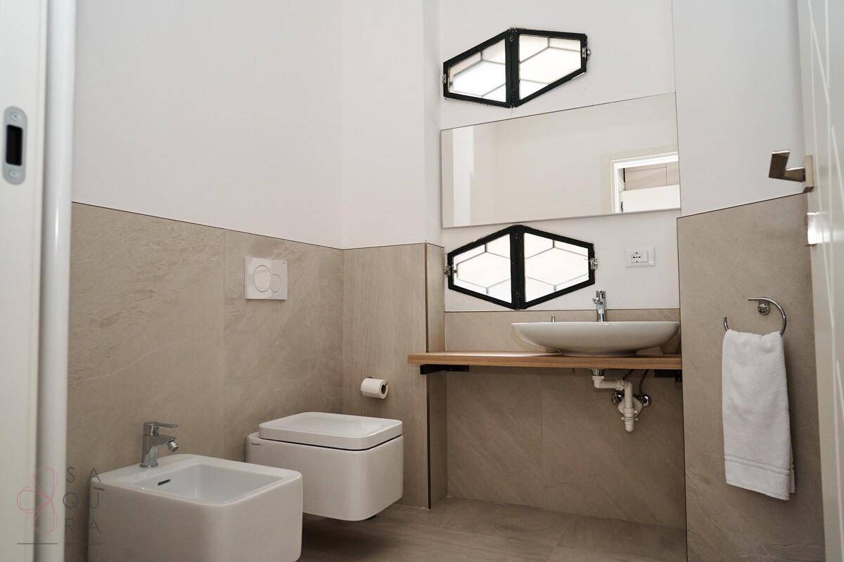 Helles Badezimmer mit modernem Waschbecken, Toilette und Bidet, in neutralen Farben gehalten.