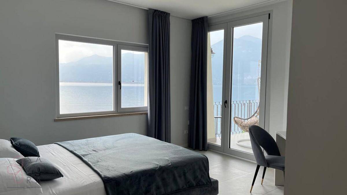 Schlafzimmer mit Doppelbett, Schreibtisch und direktem Zugang zum Balkon mit Seeblick.