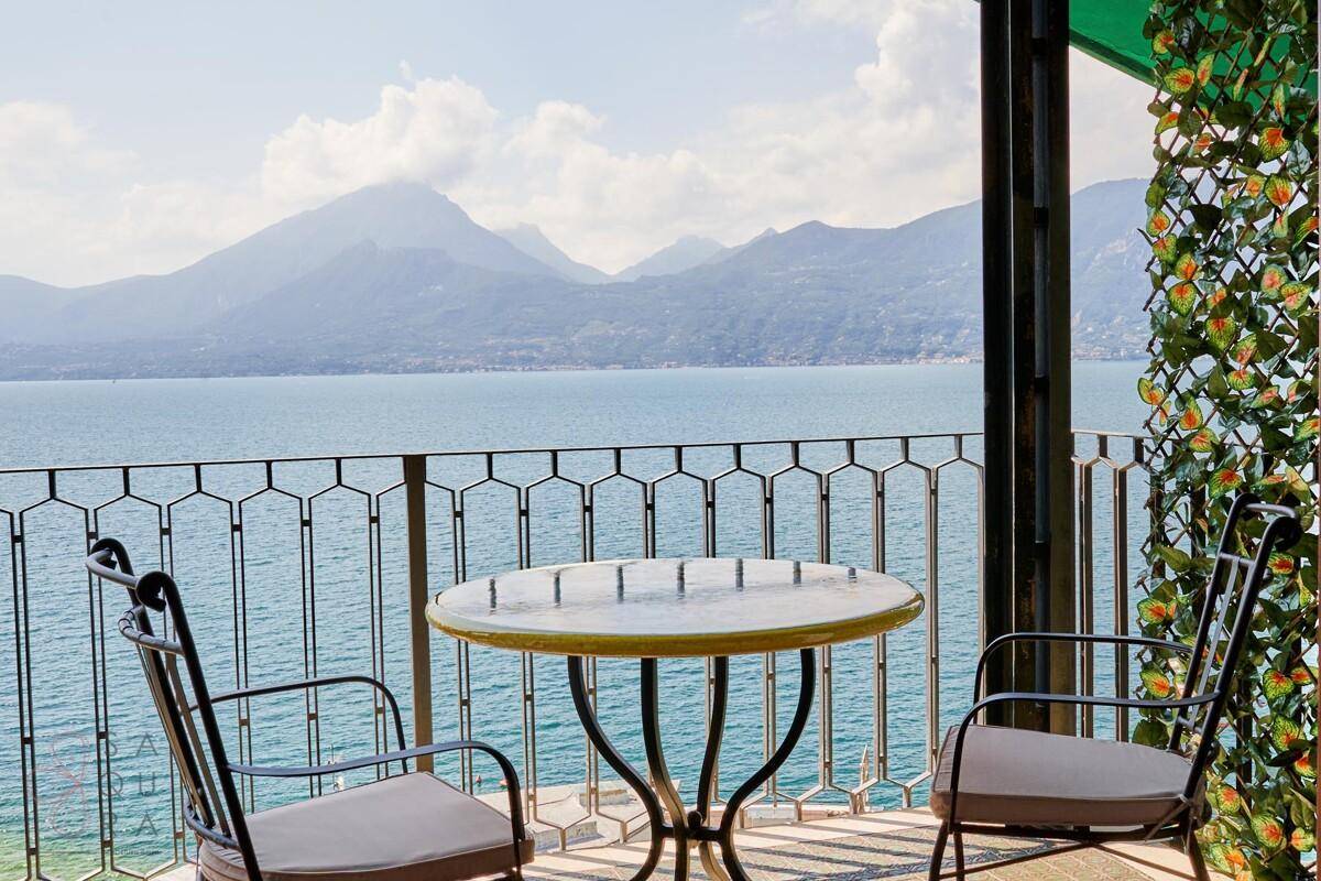 Gemütlicher Balkon mit Sitzgelegenheiten und spektakulärem Blick auf den See und die Berge.
