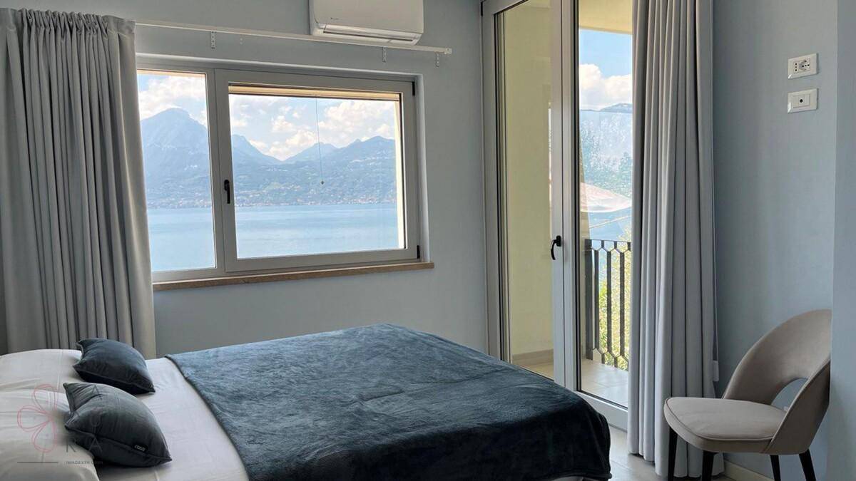 Schlafzimmer mit Doppelbett, Klimaanlage und Panoramablick auf den See und die Berge.