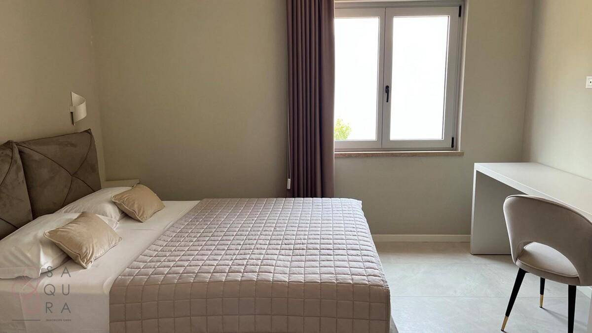 Helles Schlafzimmer mit Doppelbett und Schreibtisch, modern und funktional eingerichtet.