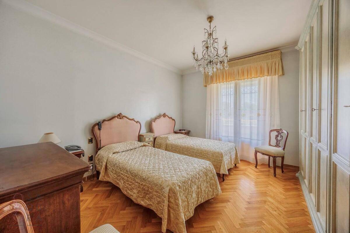 Helles Schlafzimmer mit zwei Einzelbetten, Parkettboden und großem Einbauschrank.