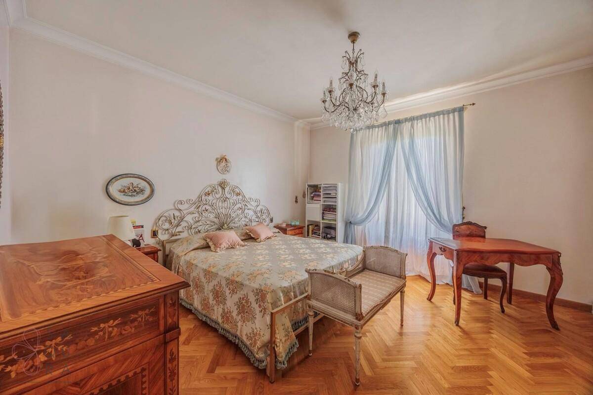 Elegantes Schlafzimmer mit Doppelbett, Parkettboden und klassischem Mobiliar.