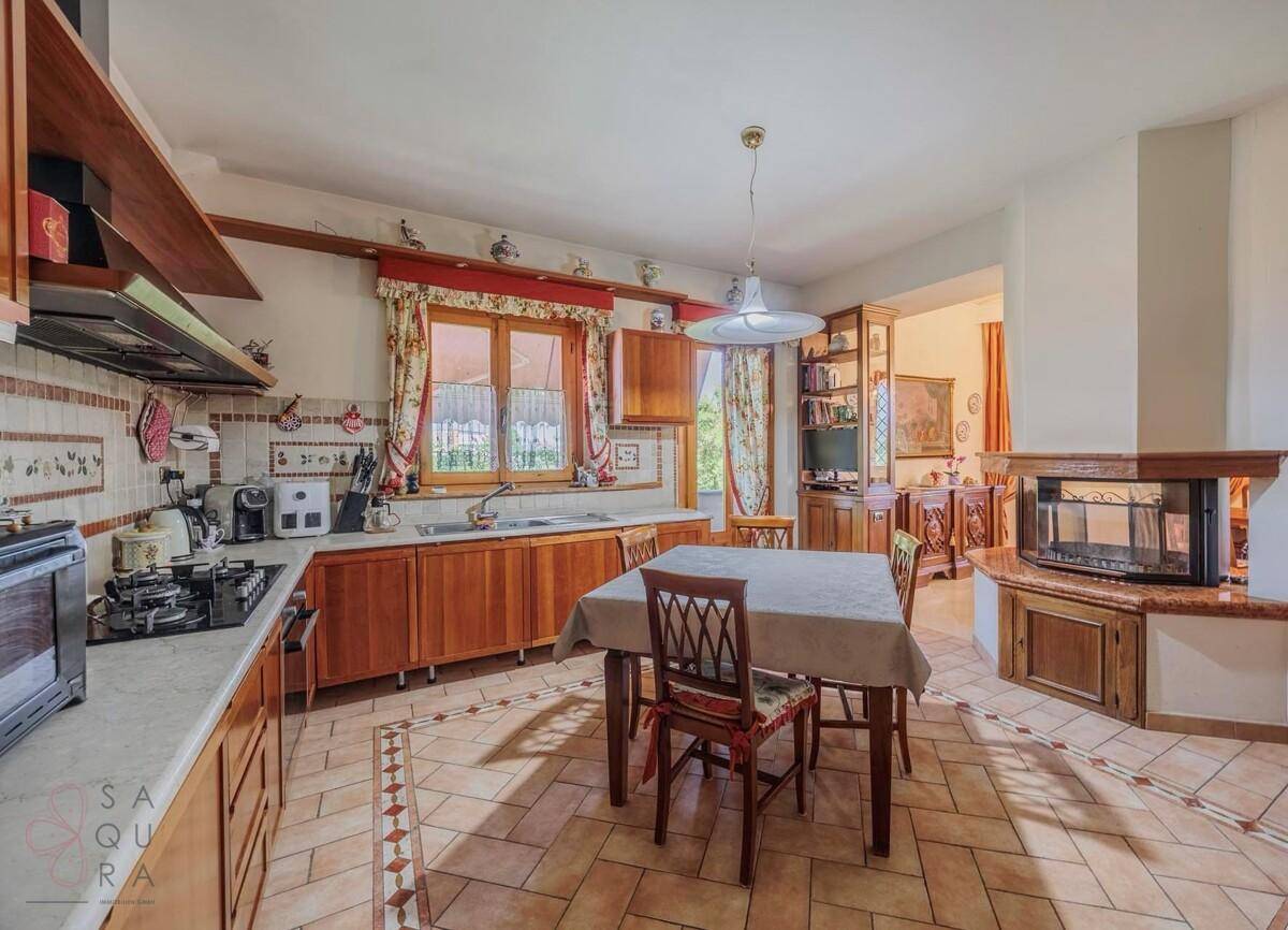 Traditionelle Wohnküche mit Holzeinbauten, Fliesenboden und Essbereich am Kamin.