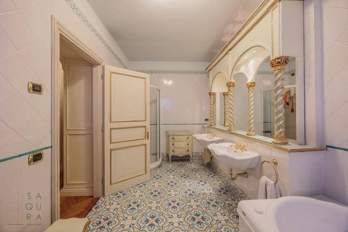 Geräumiges Badezimmer mit Doppelwaschbecken, Dusche und dekorativen Fliesen.