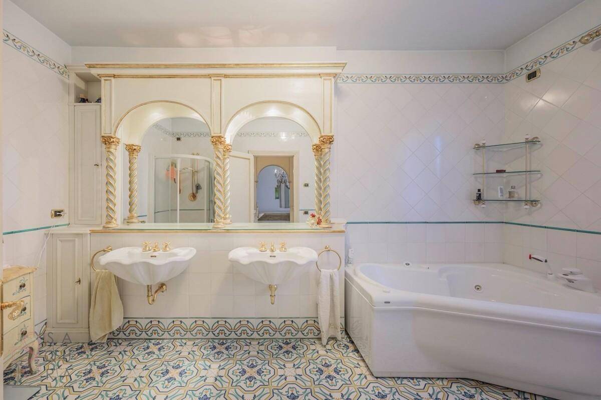 Elegantes Badezimmer mit Doppelwaschbecken, Whirlpool-Badewanne und kunstvollen Fliesen.