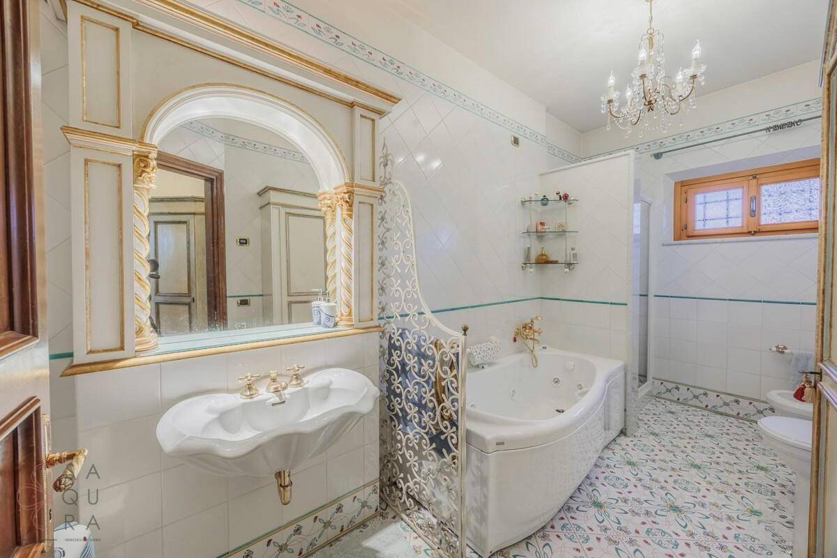 Luxuriöses Badezimmer mit Whirlpool-Badewanne, dekorativen Fliesen und goldenen Akzenten.