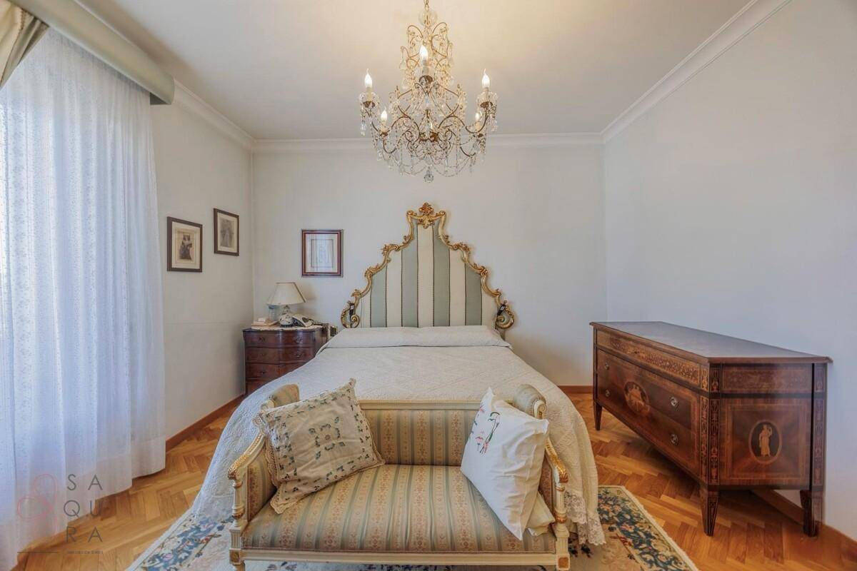 Helles Schlafzimmer mit Doppelbett, Parkettboden und klassischer Einrichtung.