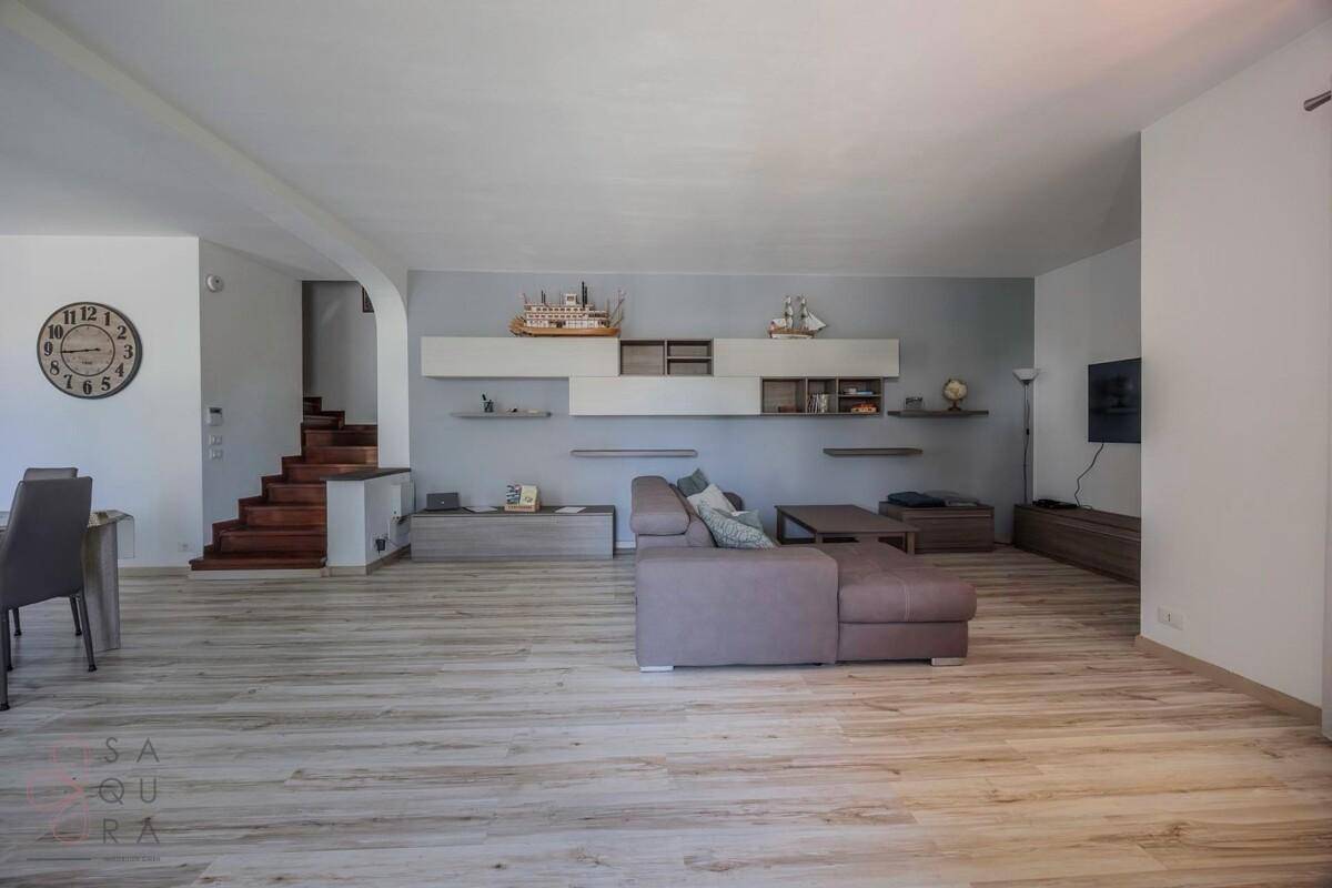 Offener Wohnbereich mit bequemer Couch, Wandregalen und Blick auf den Essbereich.