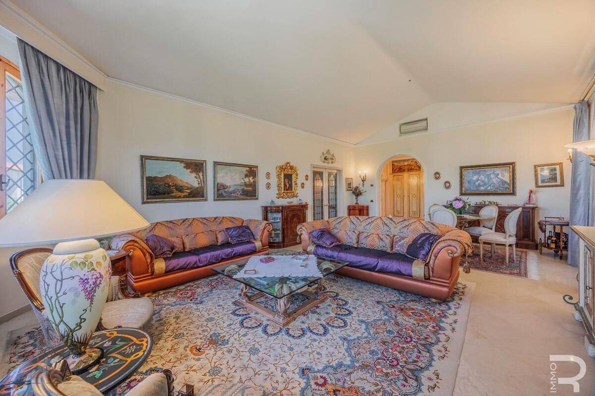 Geräumiges Wohnzimmer mit zwei großen Sofas, einem Glastisch und einem Durchgang zum Essbereich.