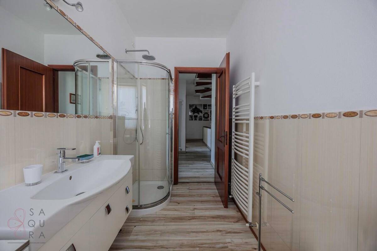 Badezimmer mit Duschkabine, Einzelwaschbecken und beheiztem Handtuchhalter.