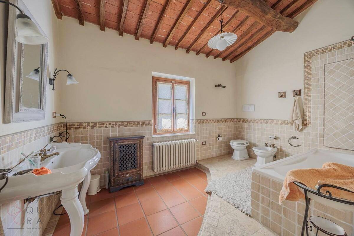 Traditionelles Badezimmer mit Terrakottafliesen, Doppelwaschbecken und Badewanne.