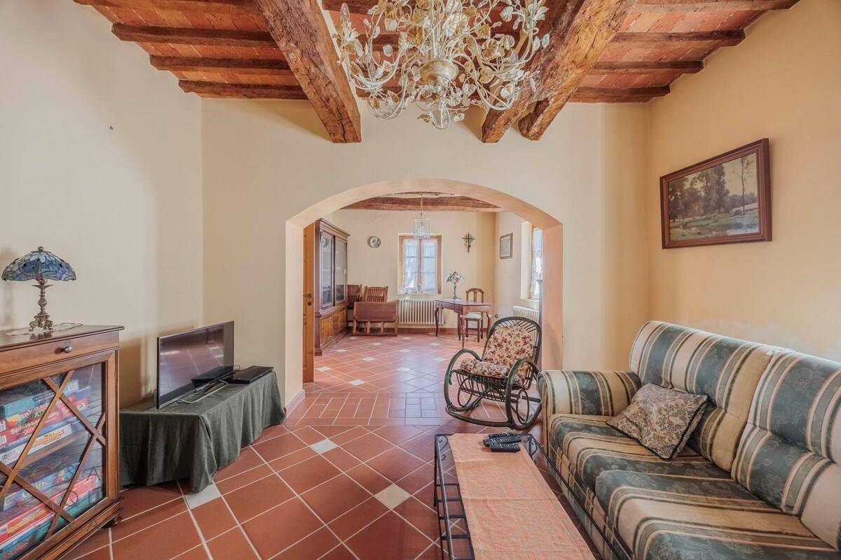 Helles Wohnzimmer mit traditionellem Kamin und Terrakottafliesen, verbunden mit einem Essbereich.