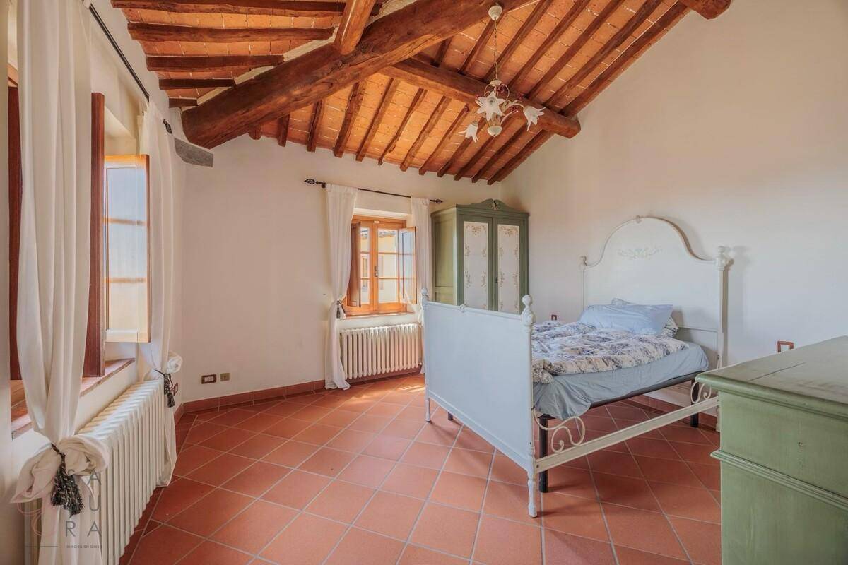 Helles Schlafzimmer mit Terrakottafliesen, Holzbalkendecke und traditionellen Holzfenstern.
