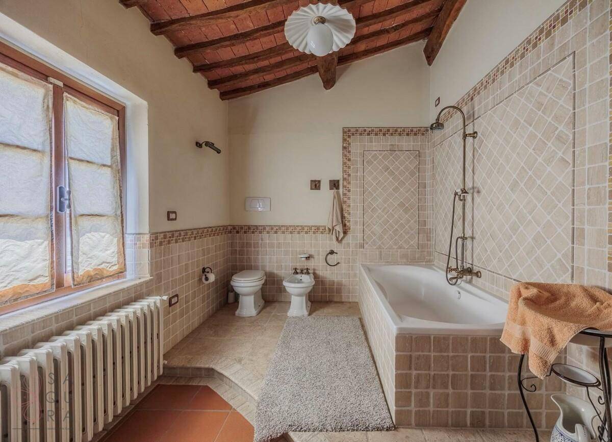 Badezimmer mit Badewanne, Bidet und Terrakottafliesen, ausgestattet mit traditionellen Armaturen.