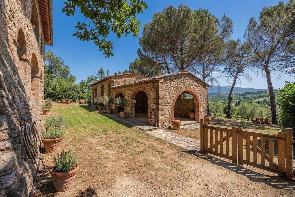 Mediterraner Gartenbereich mit Steingebäuden, Terrakottatöpfen und Blick auf die Landschaft.
