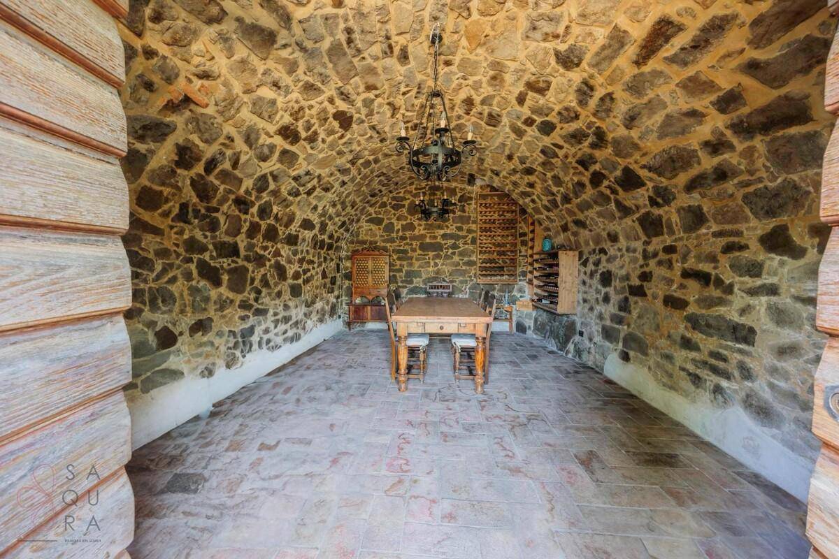 Rustikaler Weinkeller mit Gewölbedecke aus Naturstein und traditionellem Esstisch.