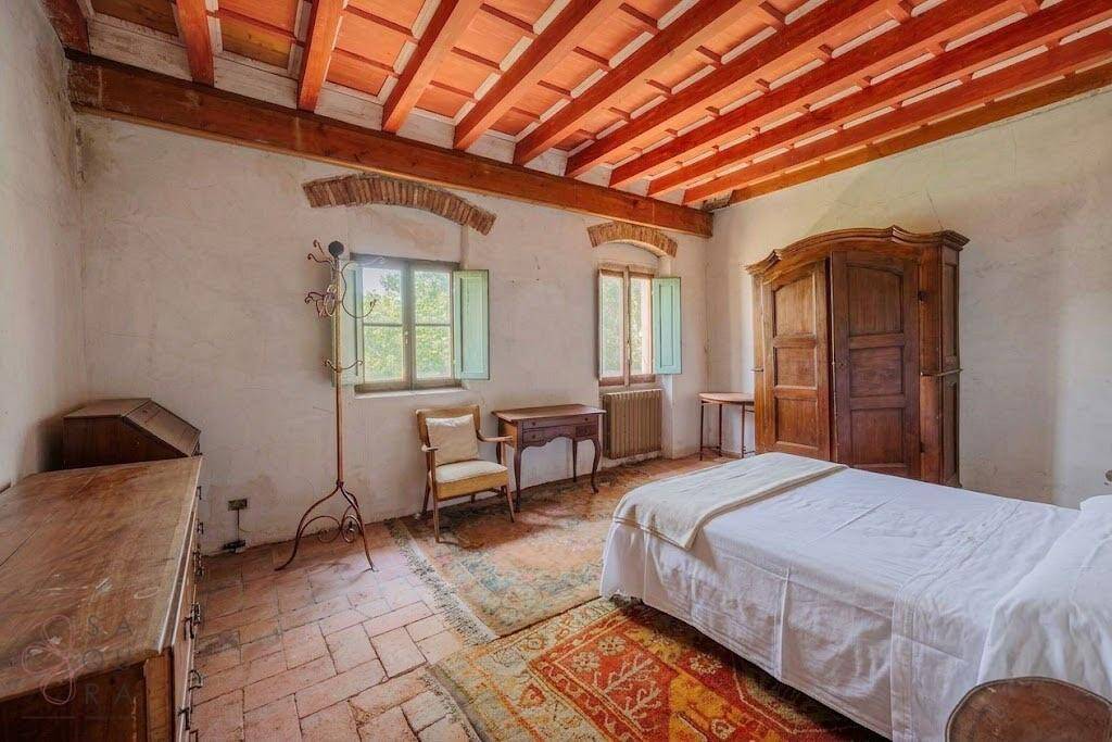 Geräumiges Schlafzimmer mit Holzbalkendecke, Terrakottafliesen und antiken Holzmöbeln.
