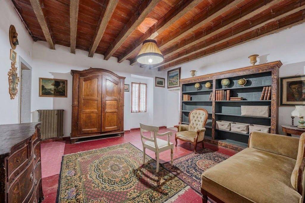 Schlafzimmer mit Holzbalkendecke, Teppichboden und antiken Holzmöbeln.
