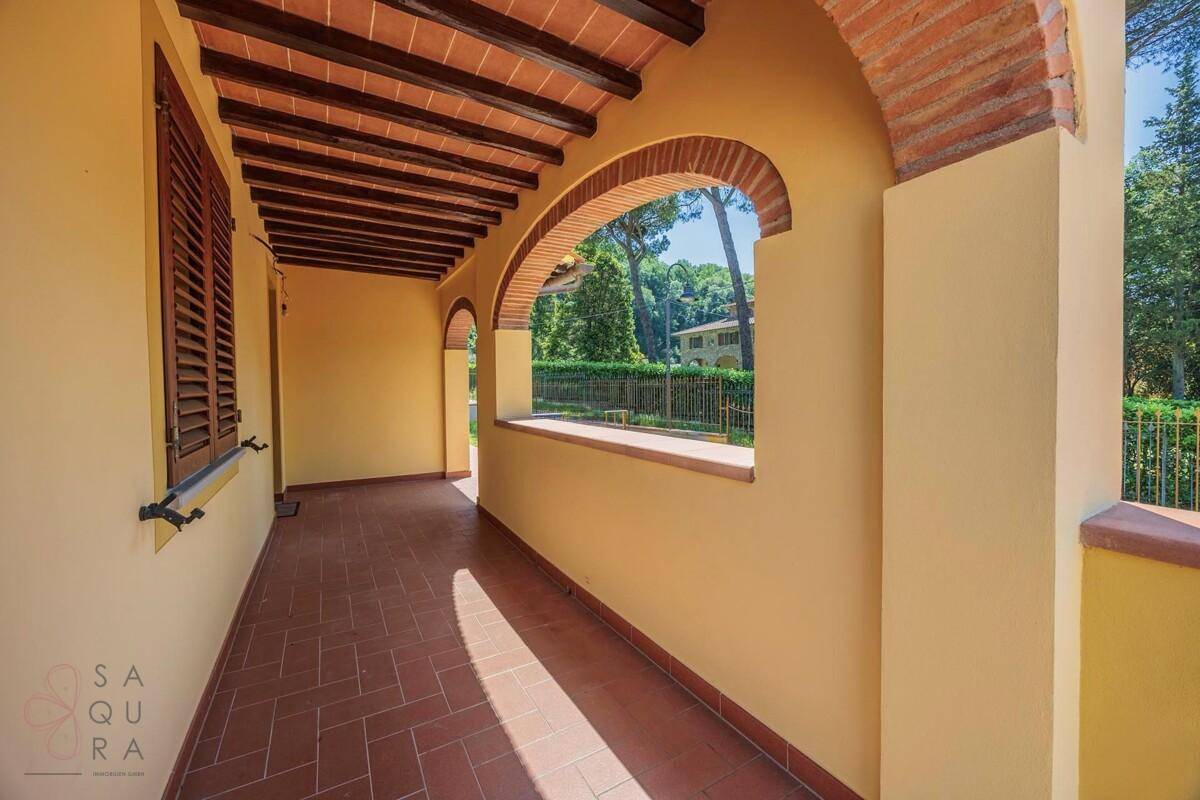 Lange, überdachte Loggia mit Ziegelbögen und traditionellen Holzbalken an der Decke.