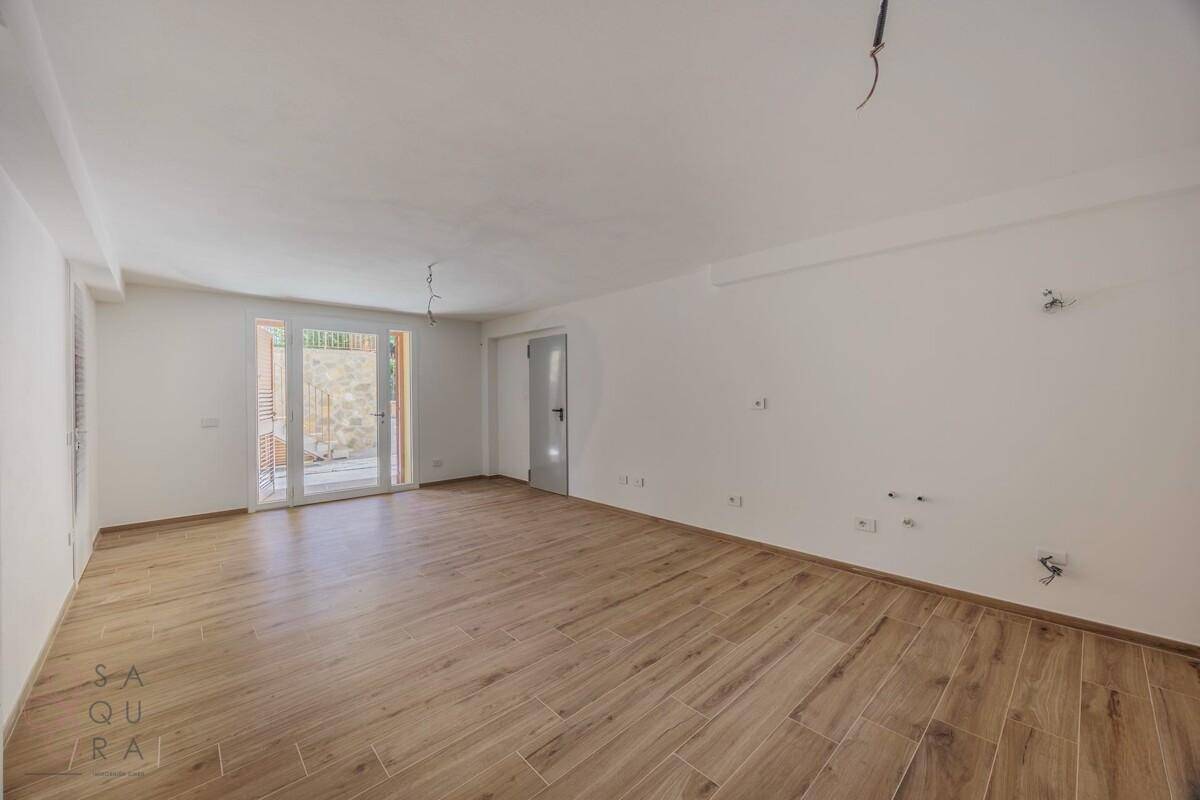 Großer, heller Raum mit Holzoptik-Fliesenboden und Zugang zu einem Außenbereich.