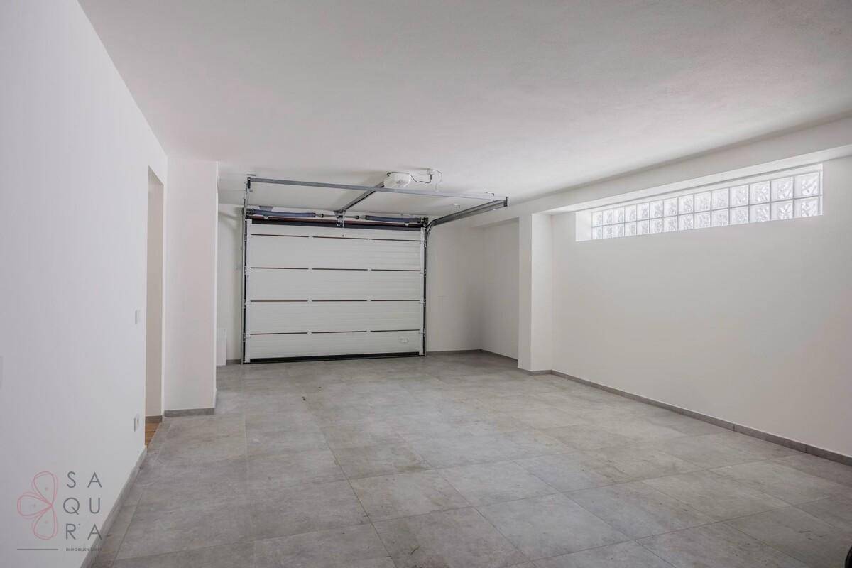 Geräumige Garage mit automatischem Tor, Fliesenboden und Oberlichtfenstern.