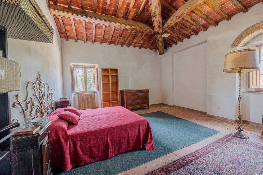 Großes Schlafzimmer mit Holzbalkendecke, Teppich und traditioneller Einrichtung.