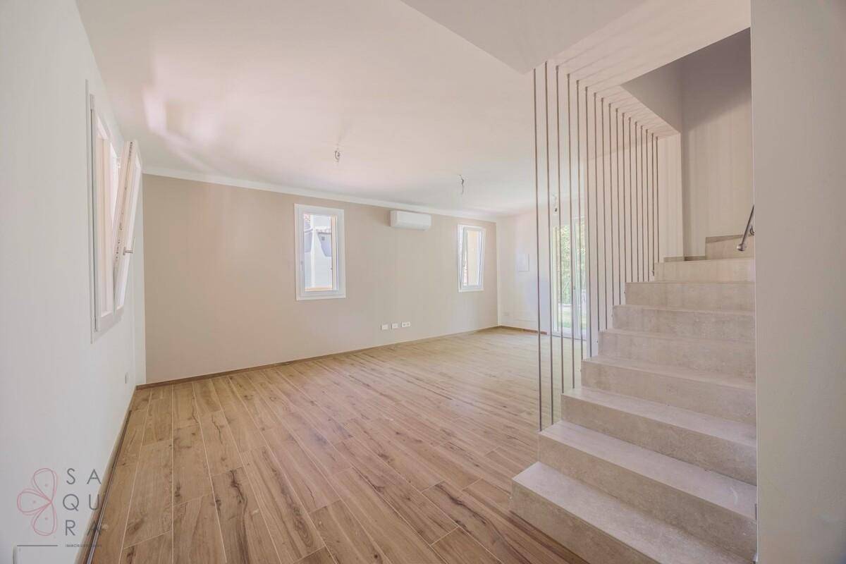 Heller Wohnbereich mit Holzoptik-Fliesenboden und moderner Treppe mit Drahtgeländer.