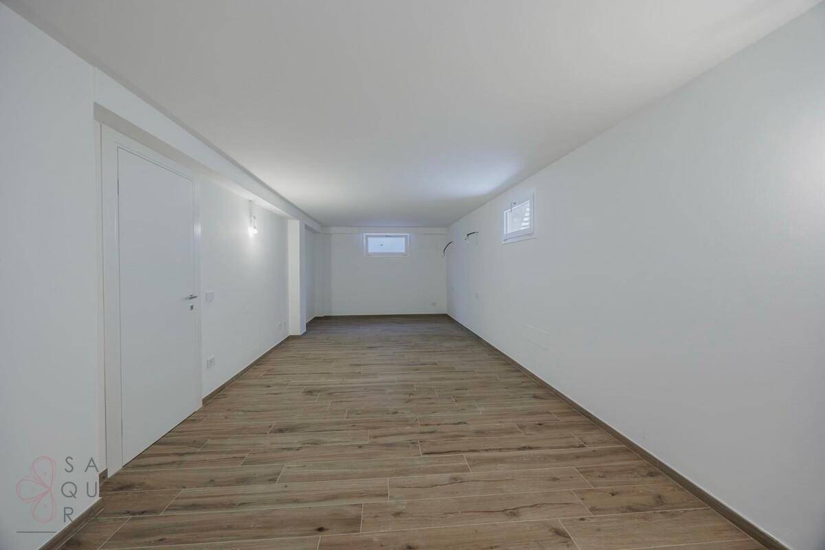 Langer Kellerraum mit Holzoptik-Fliesenboden und kleinen Fenstern für Tageslicht.