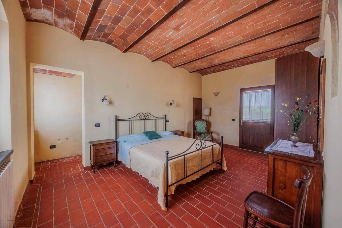 Schlafzimmer mit schmiedeeisernem Bett, Holzmöbeln und gewölbter Ziegeldecke.