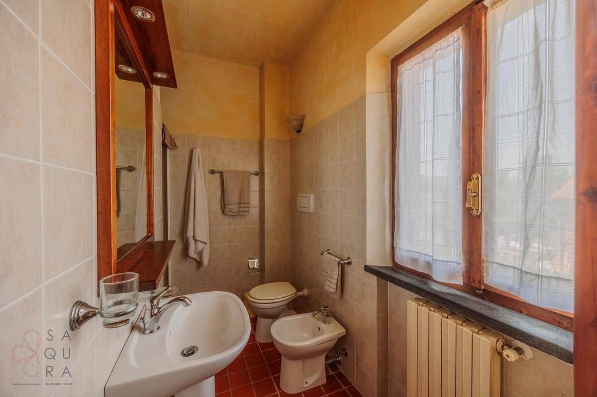 Funktionales Badezimmer mit Fenster, Heizkörper und traditionellen Armaturen.