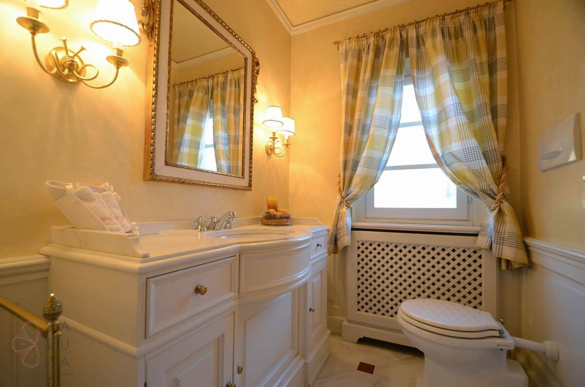 Elegantes Gäste-WC mit Waschtisch, Spiegel und Fenster in warmen Farbtönen.