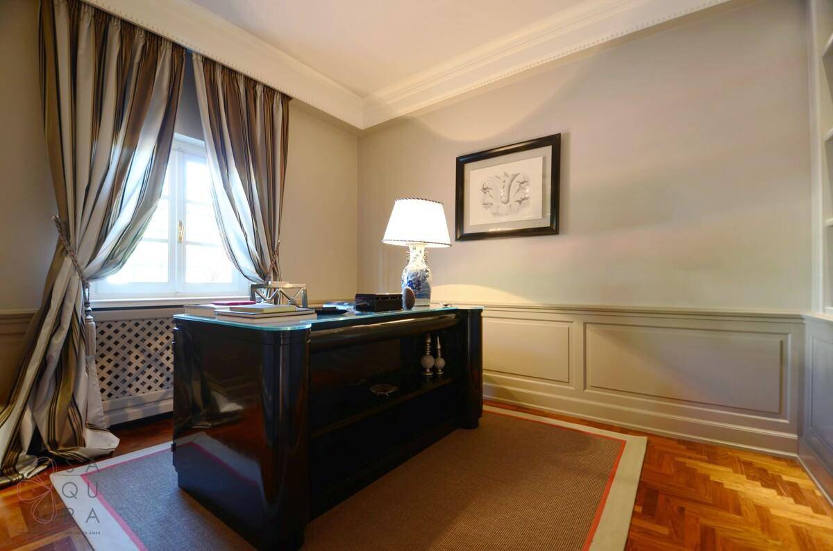 Klassisches Arbeitszimmer mit Holzboden, elegantem Schreibtisch und gestreiften Vorhängen.