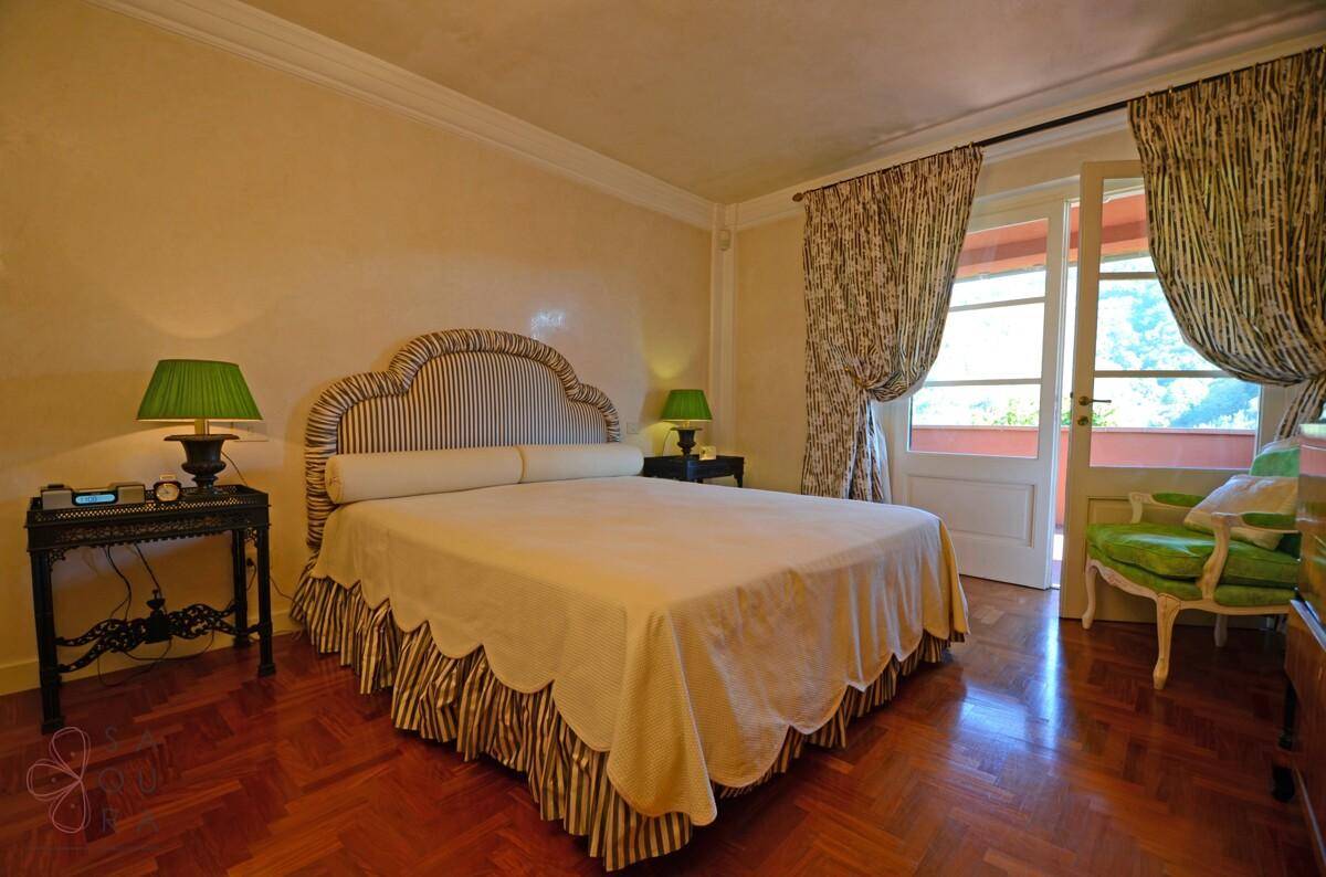 Elegantes Schlafzimmer mit Holzboden, gestreiftem Kopfteil und Zugang zum Balkon.