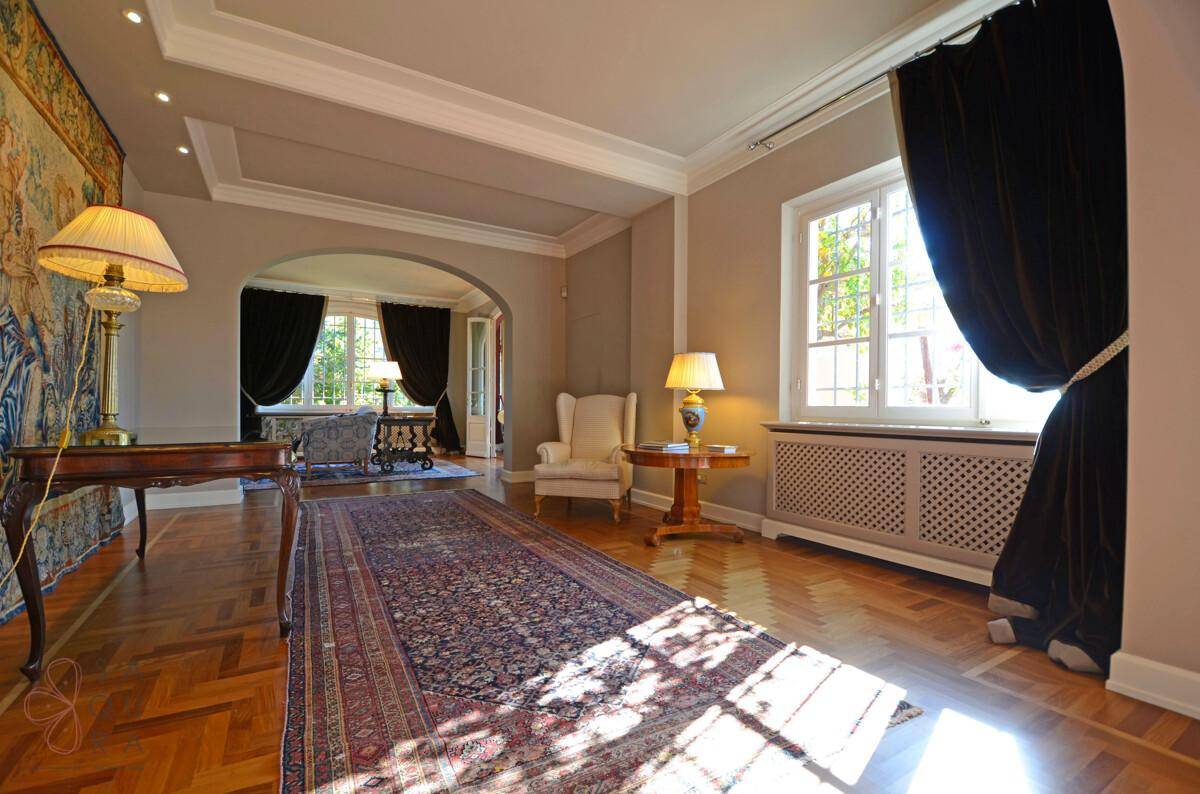 Elegantes Wohnzimmer mit Fischgrätparkett, hohen Decken und klassischer Einrichtung.